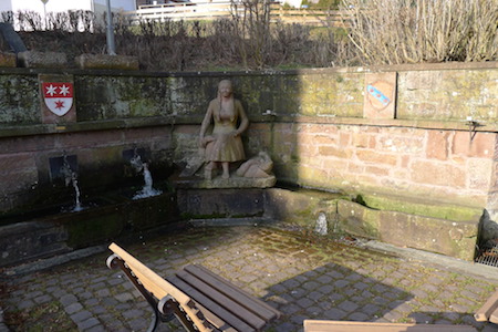 Brunnen mit Steinfiguren und Wappen.