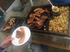 Bratkartoffeln, Steaks und Wurst liegen auf dem Grill bereit.